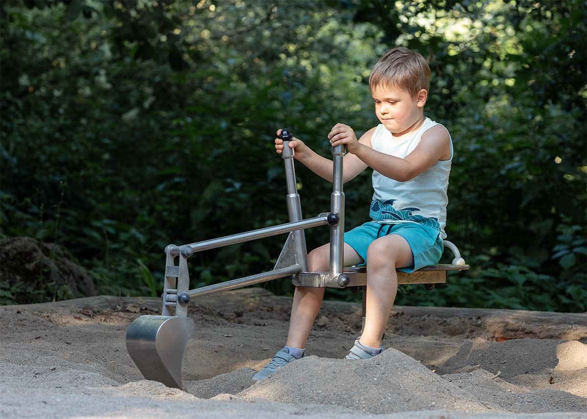 Boy sitting on a digger in a sand pit