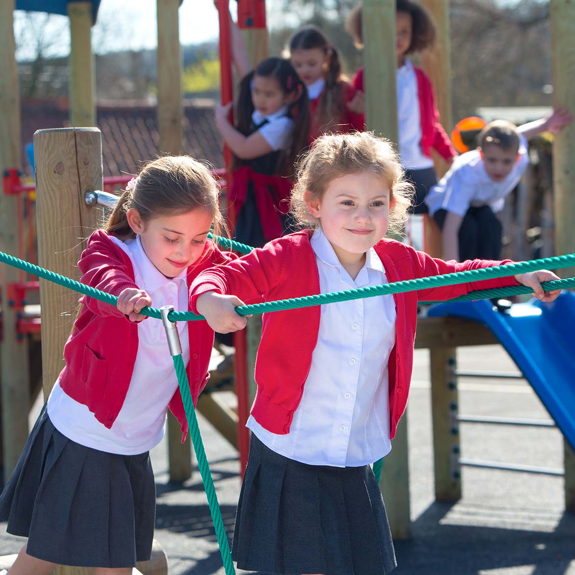 Two girls walking on rope bridge at school