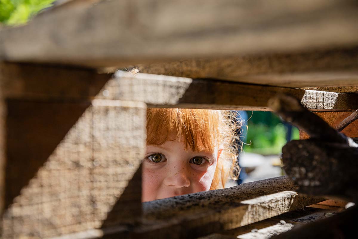 Girl peeping through a pile of wood