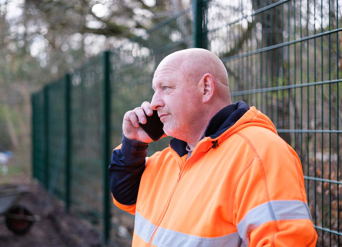 Lee talking on mobile next to fencing