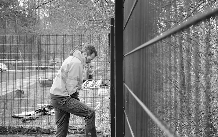 A man digging near playground fencing