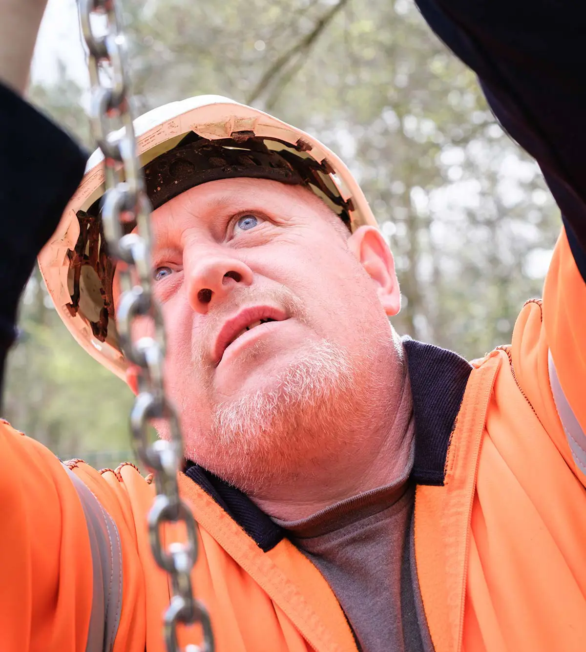 Playground safety inspector examining equipment chains during installation inspection in South England