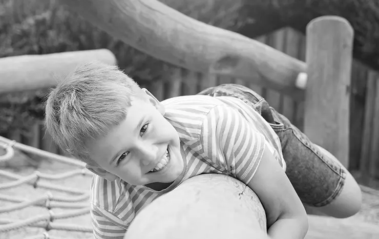 Young boy playing on natural wood play structure